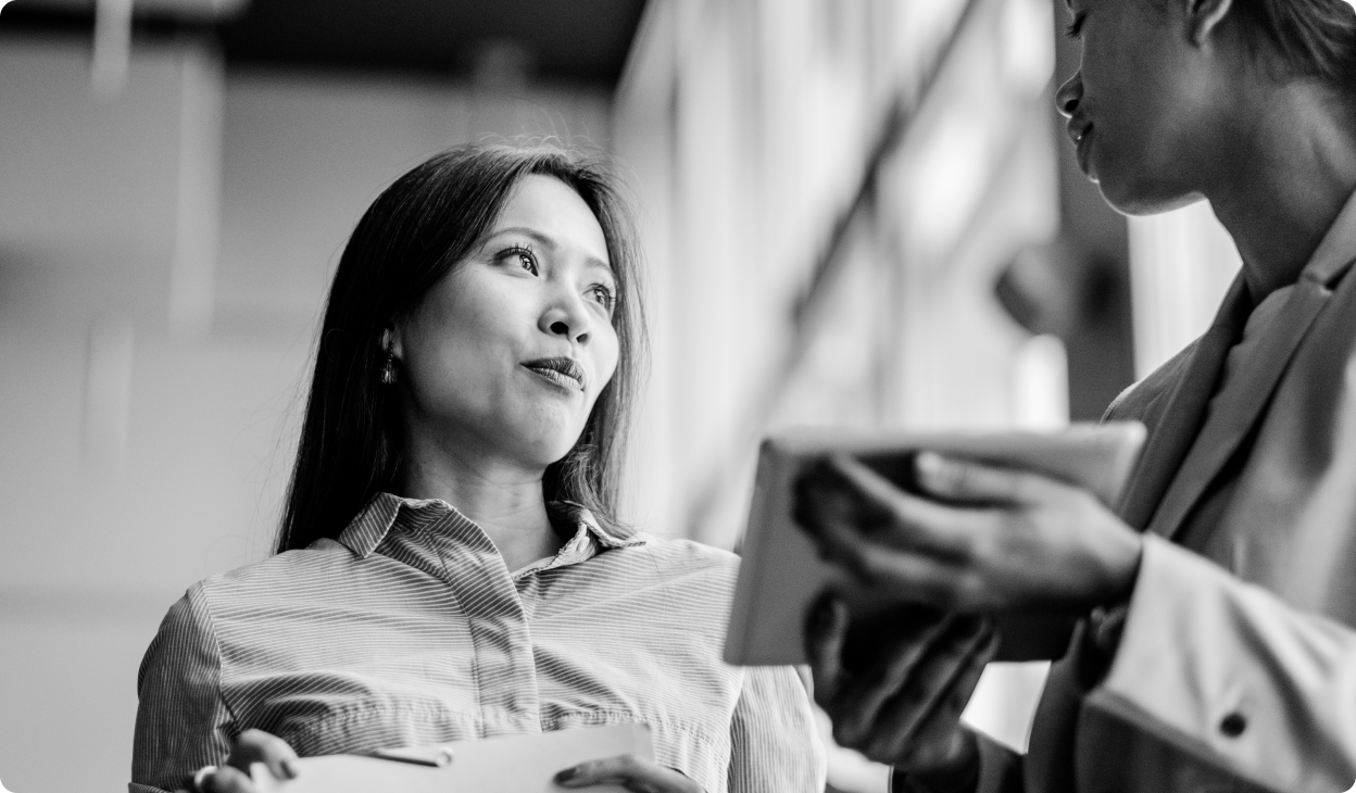 Two people talking while holding tablets. 