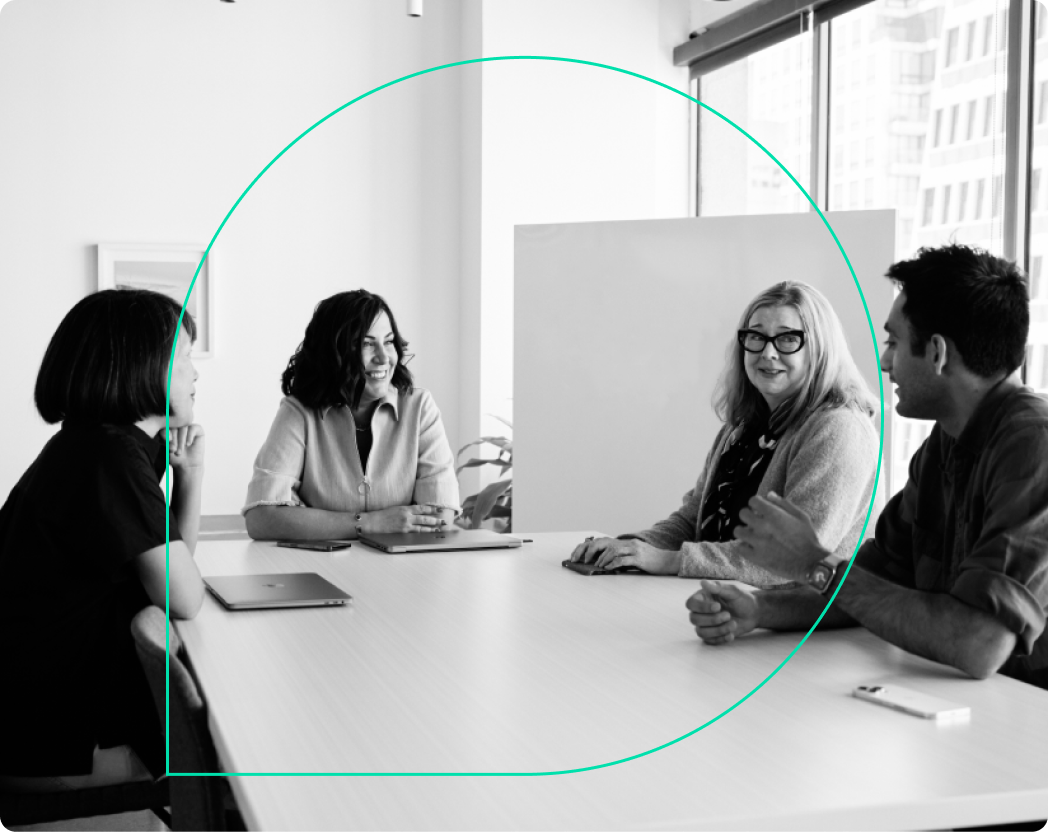 A group of colleagues sitting around a large table, with the Grammarly logo in the center