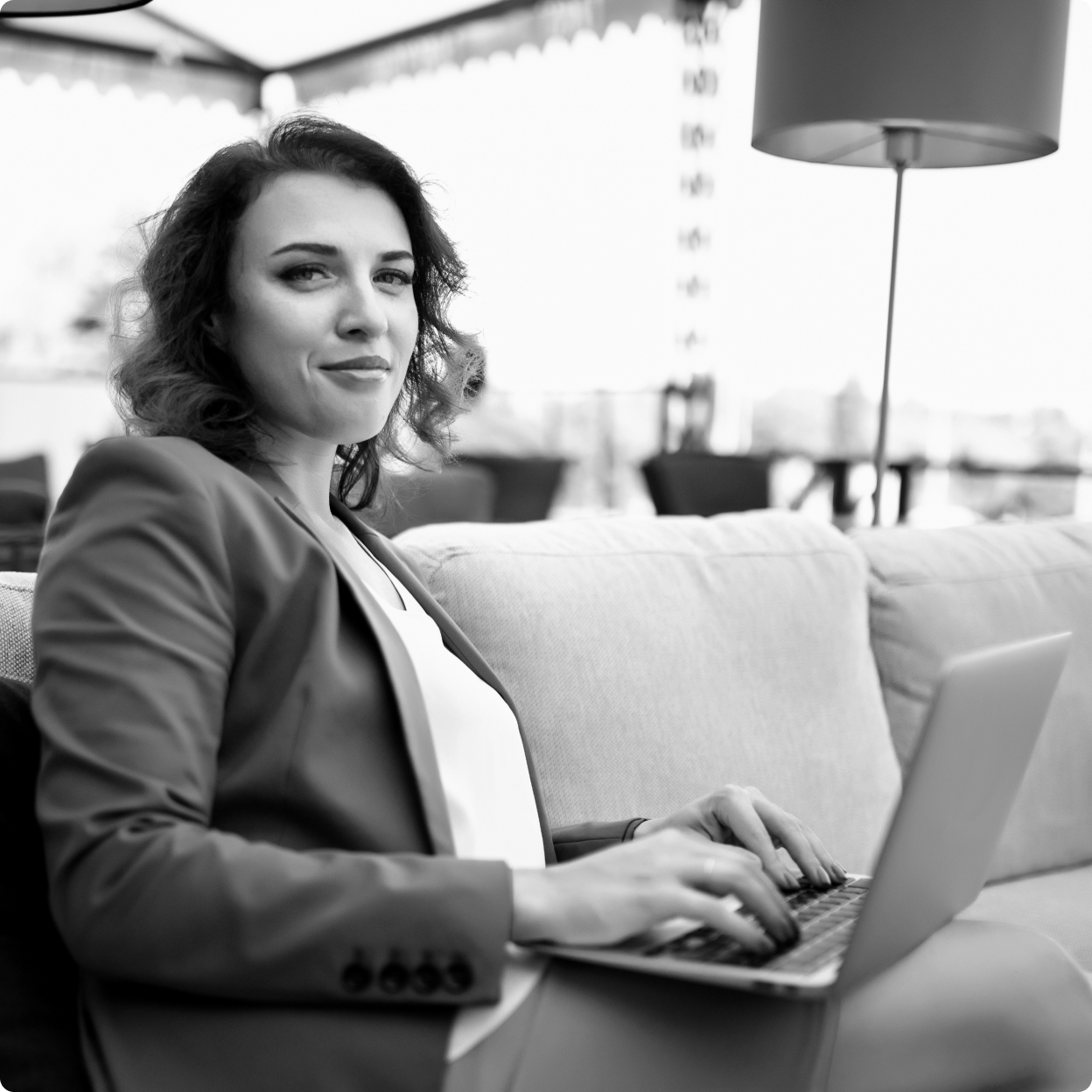 A person sits on a couch while working on a laptop. 